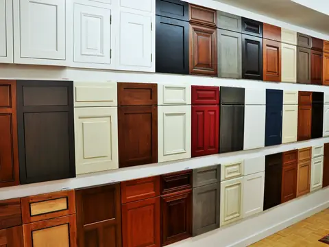 A showroom wall of cabinet door samples in white, cream, cherry, grey, red and navy
